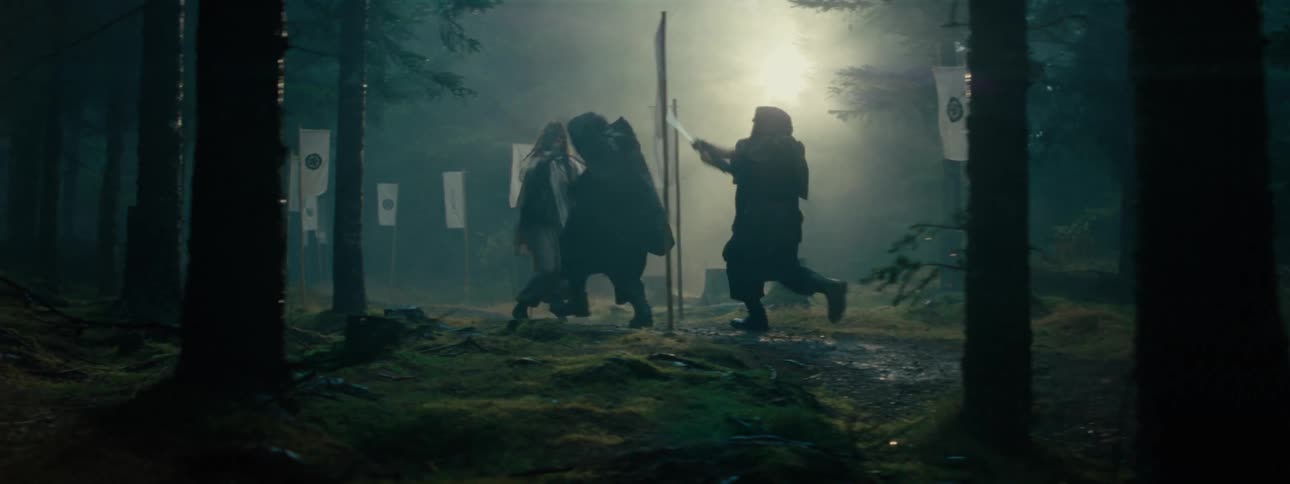 Three men engage in a vigorous sword fight in the woods