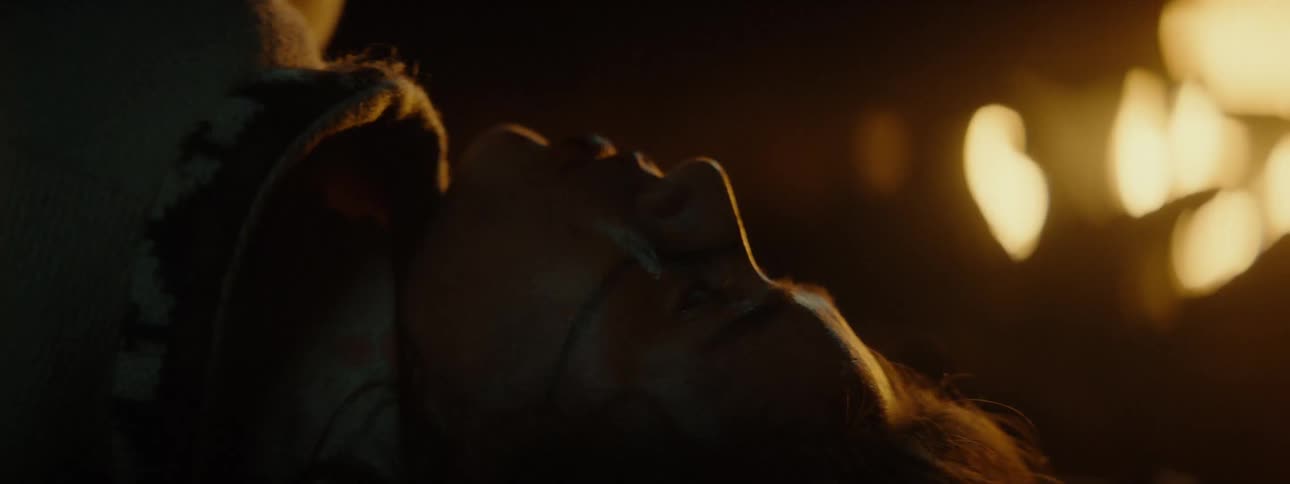 Face of a person lying on the ground with marks from fighting by a fire at night
