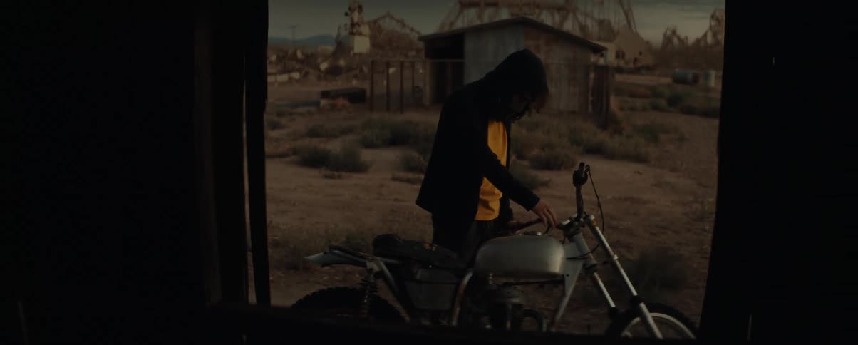 A man checks the fuel in a motorcycle outside of an open door