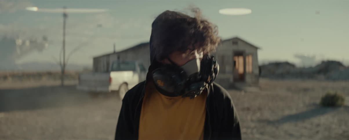 A man wearing a gas mask walks from the house
