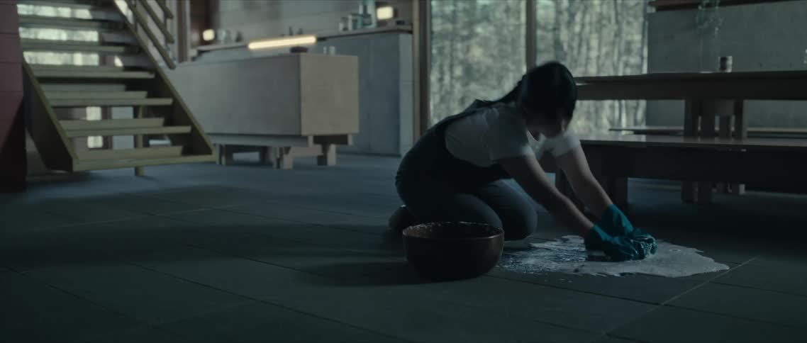 Woman kneeling on the floor wearing gloves and mopping the floor with a cloth