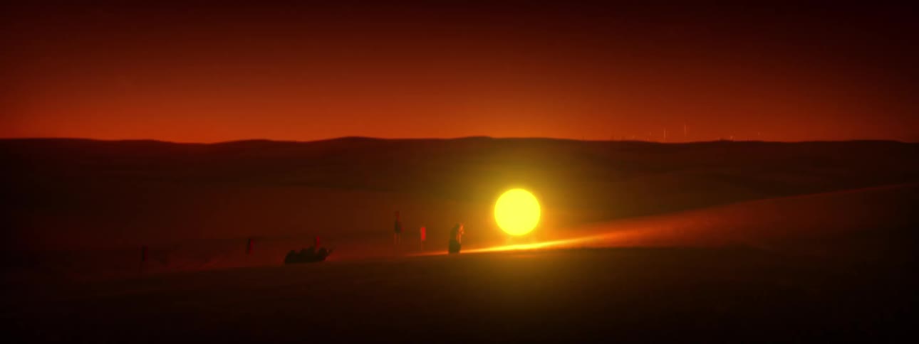 Two people approach large glowing ball of light during the night as others sit at a distance
