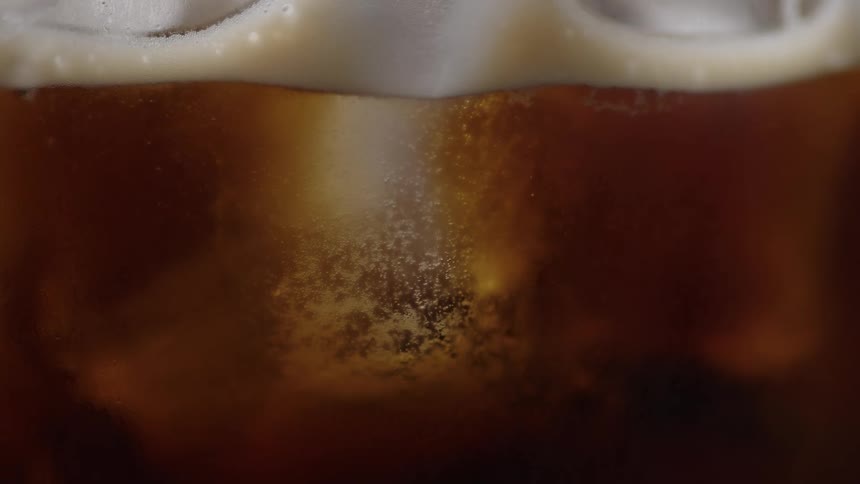 Closeup of a drink with bubbles rising through the amber liquid