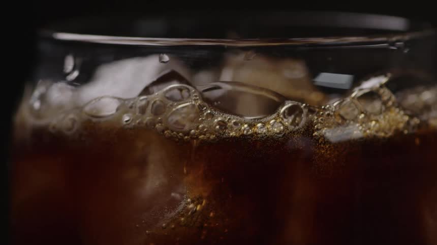 Soda is poured into a glass of ice