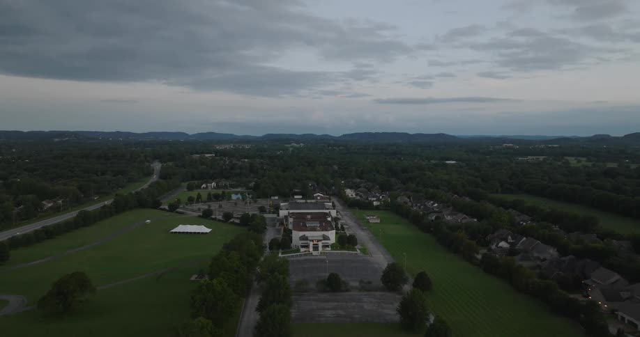 An aerial view gave a white mansion and to the sides flat green fields with some trees