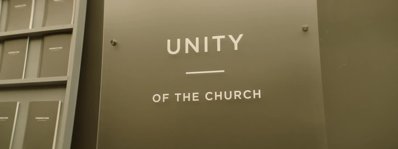 Sign reading unity of the church fixed to a wall next to a set of cabinets