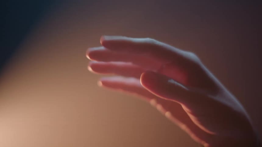 A person moves their hand and fingers in a stage light