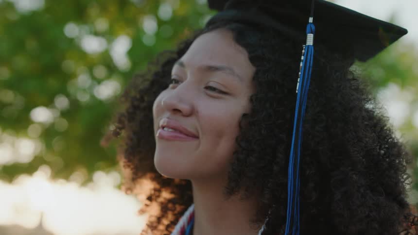 Curlyhaired woman giving a smile while wearing a graduation cap
