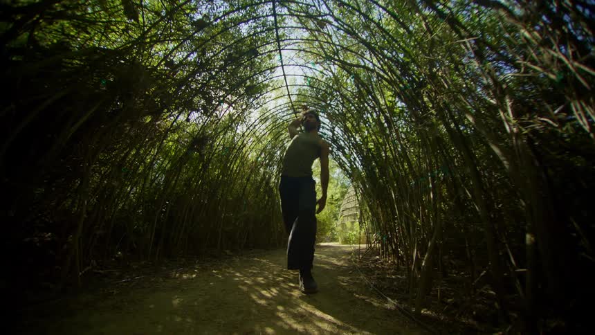 Man dancing under a bamboo tunnel