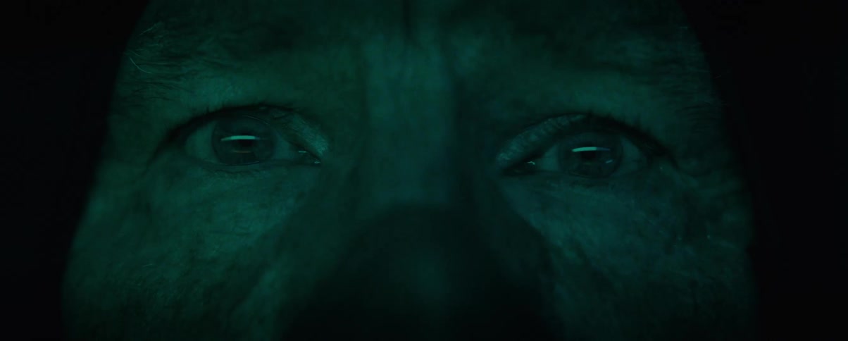 Portrait of a persons face with wide eyes and a cold light flashing on his face