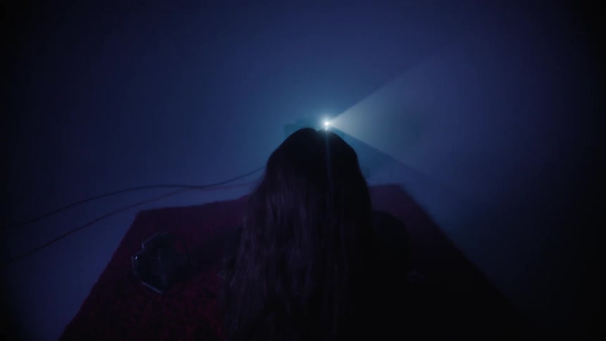 A woman has her back turned towards a tv with a white screen and there is a red light on top of the tv going to the left