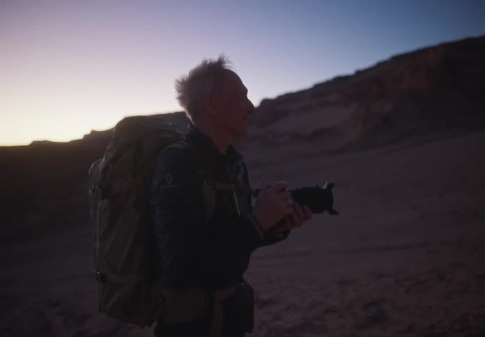 Man in a natural environment of desert mountains using a professional camera and taking photos