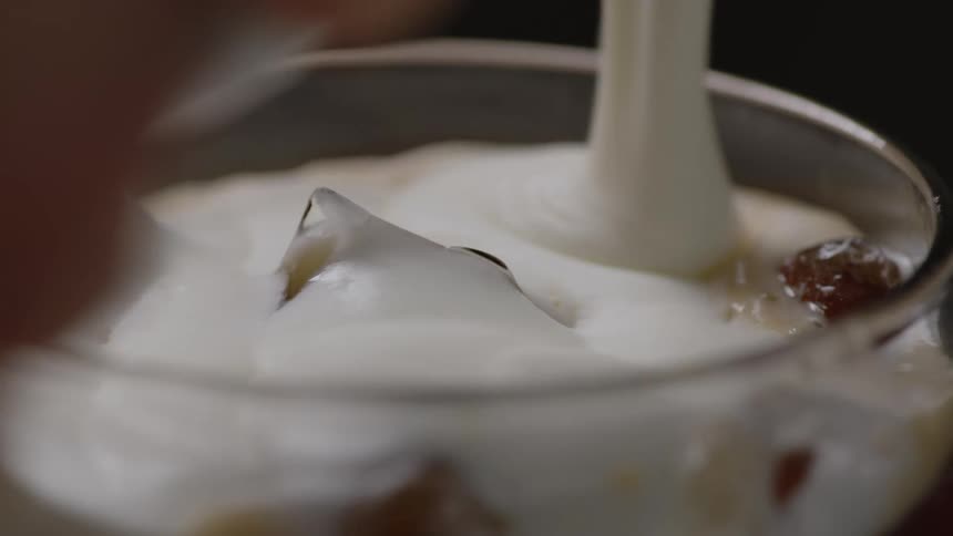 Cream is poured on the ice in the glass