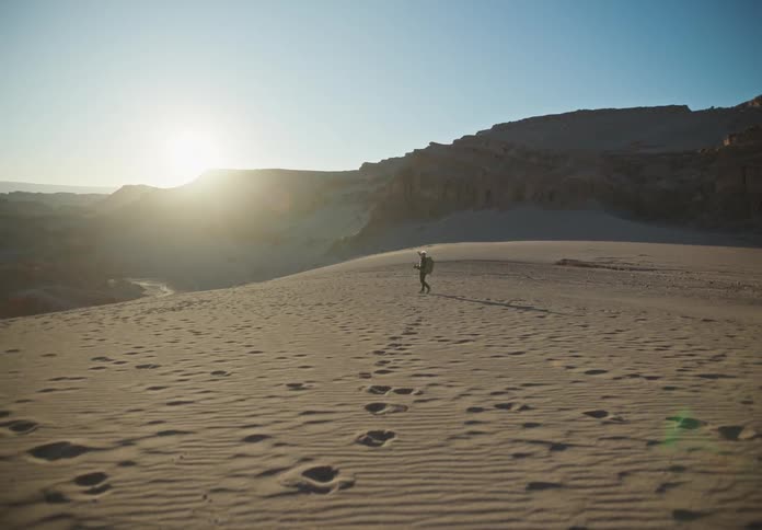 A person walking through a desert stops and takes a photo