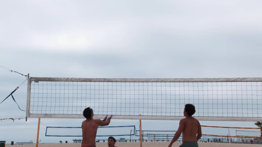 Men playing volleyball at the beach on a cloudy day