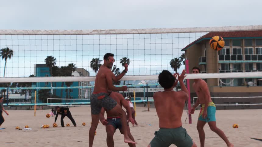 Four individuals playing beach volleyball on a sandy court
