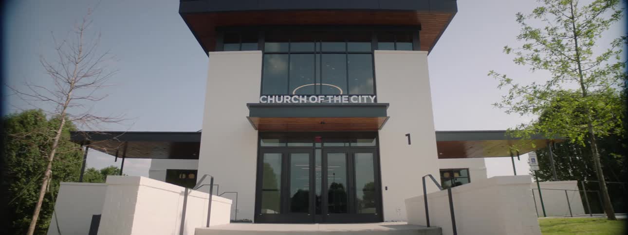 Facade of a modern building with the inscription church of the city over the main entrance surrounded by a grassy area on a sunny day