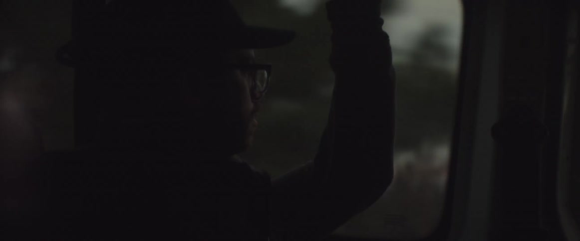 A man wearing glasses rides a train