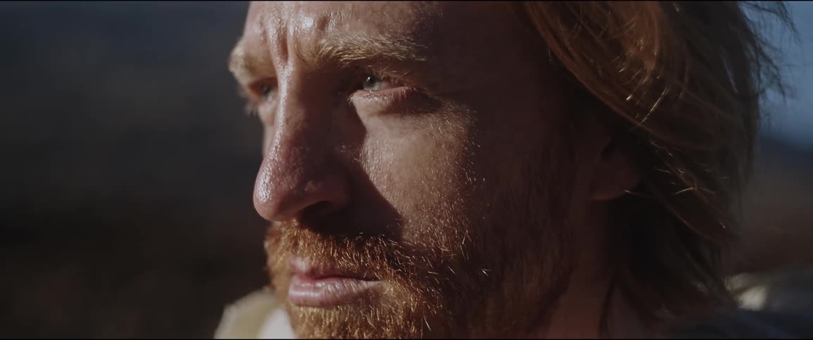 The face of a bearded man with clear eyes looking straight ahead and his skin is sweaty