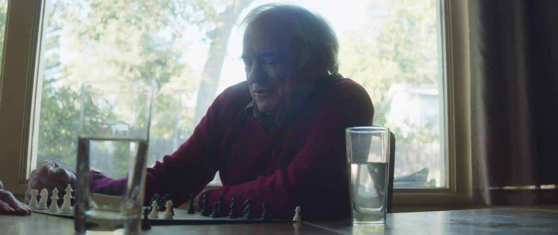 A man and an elderly woman sit at a table and are talking