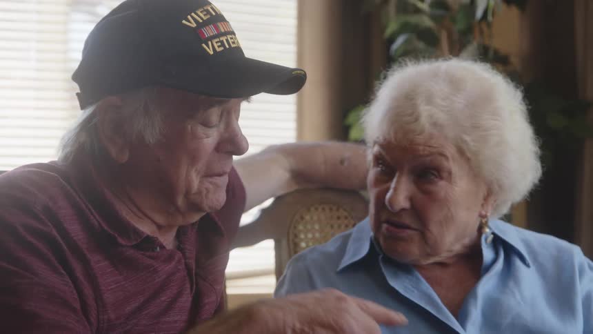 An elderly couple sitting at the dinner table at home talking to each other