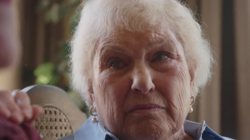 Two elderly people sitting side by side with one of them having tears in his eyes with emotion