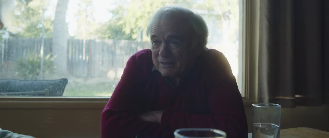 Two individuals seated at a table one facing the other one man talks smiles and laughs