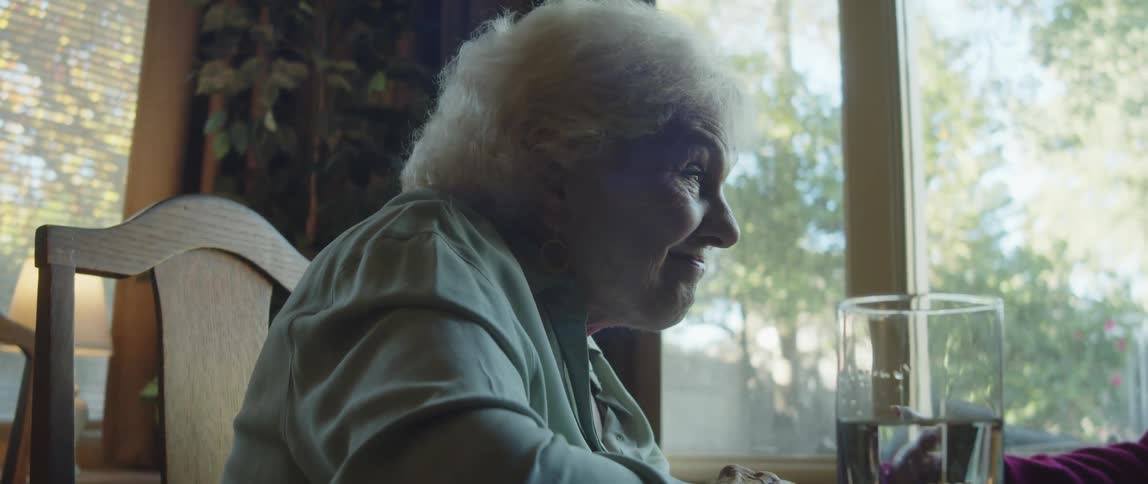 Elderly lady sitting at a table talking to another person