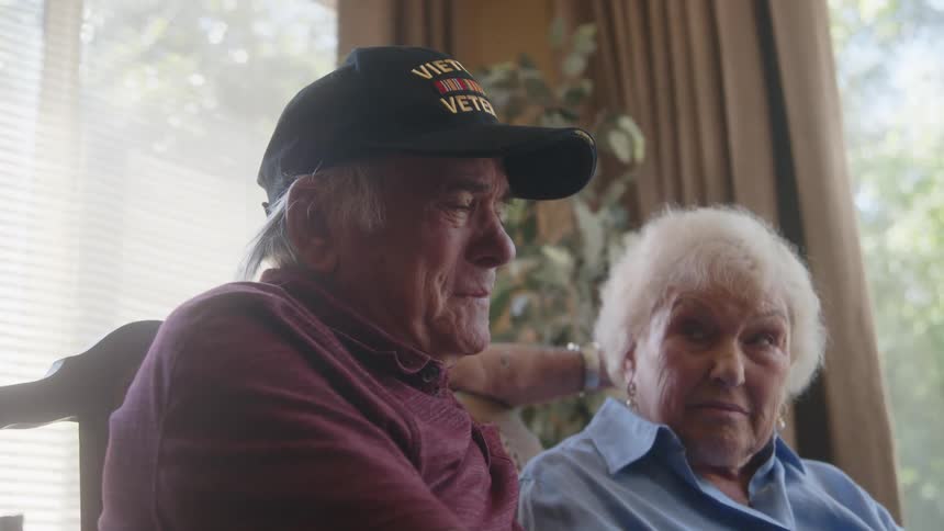 Elderly man and woman sitting side by side with the man crying emotionally