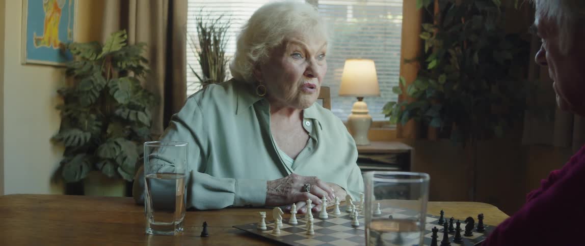 Old couple plays chess while they talk to each other