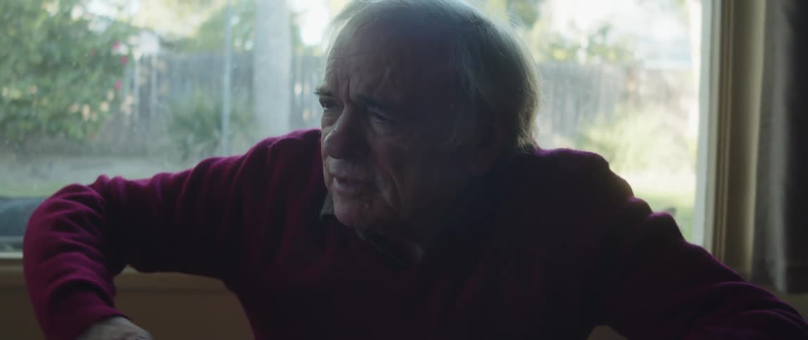 An elderly man talks with a friend in a house