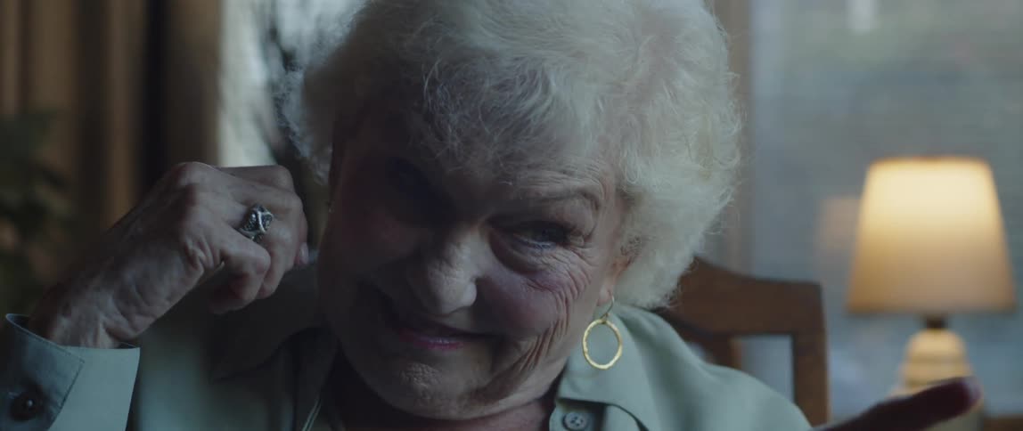 Smiling elderly lady playing chess while sitting at the table