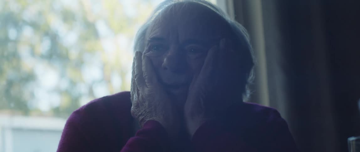 Smiling elderly man putting his hands on his face