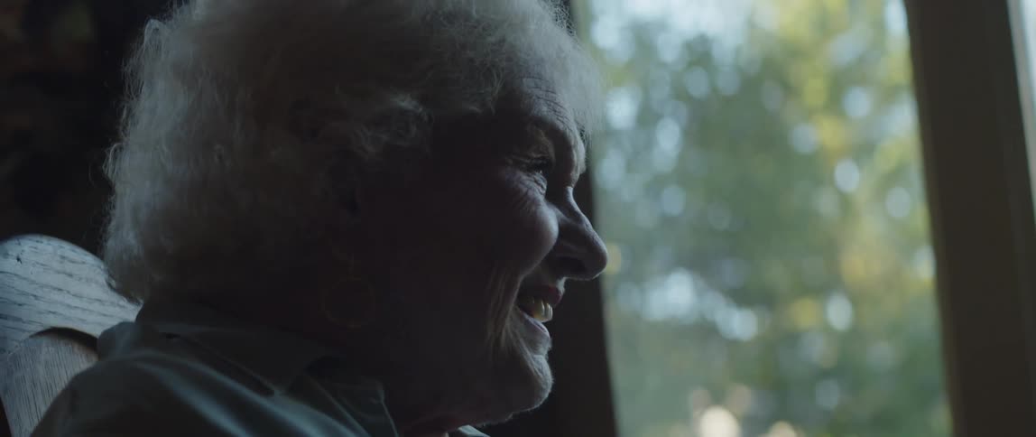 Two smiling elderly people sitting at a table talking