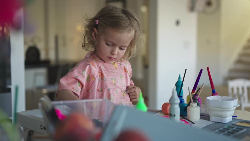 Little girl playing with painting materials on a table