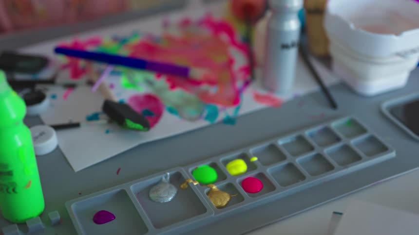 A young girl squeezes yellow paint onto a tray