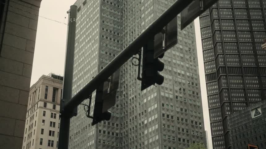 A cityscape features traffic lights against a backdrop of tall buildings