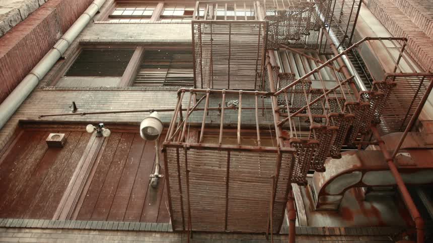 Facade of an old building with several metal fire escapes and windows highlighting the urban architecture