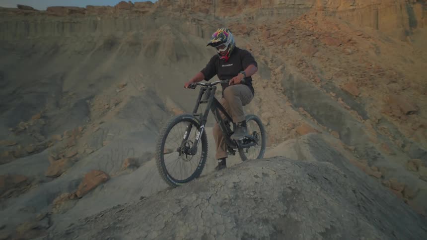 A man begins to ride his mountain bike down a mountainous terrain