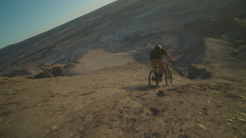 A man rides a bicycle down the slope of a mountain