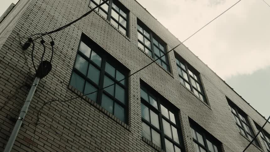 Facade of a building with windows in an alley against a cloudy sky