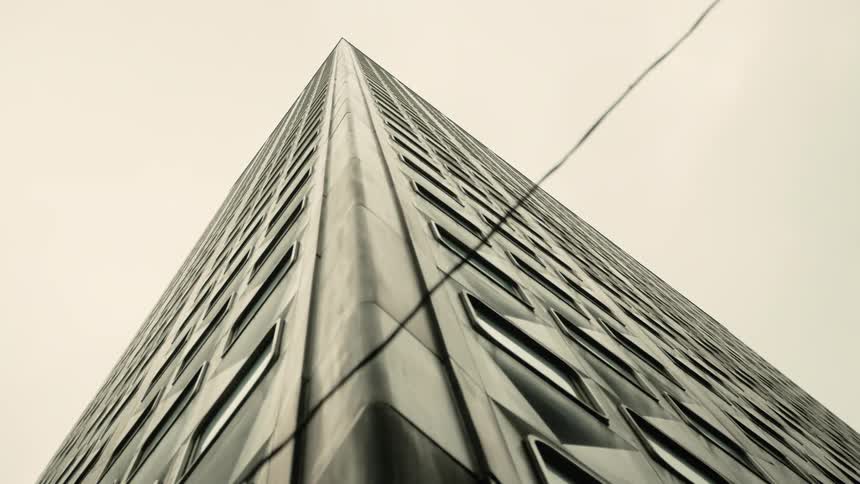 Upward view of a modern patterned building against a cloudy sky