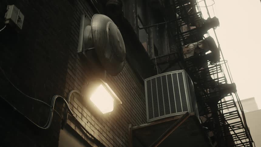 Upward view of a light on a wall of a residential building on a foggy day
