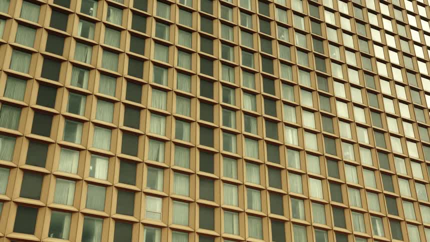 A modern building facade with a repetitive grid of windows and brown panels