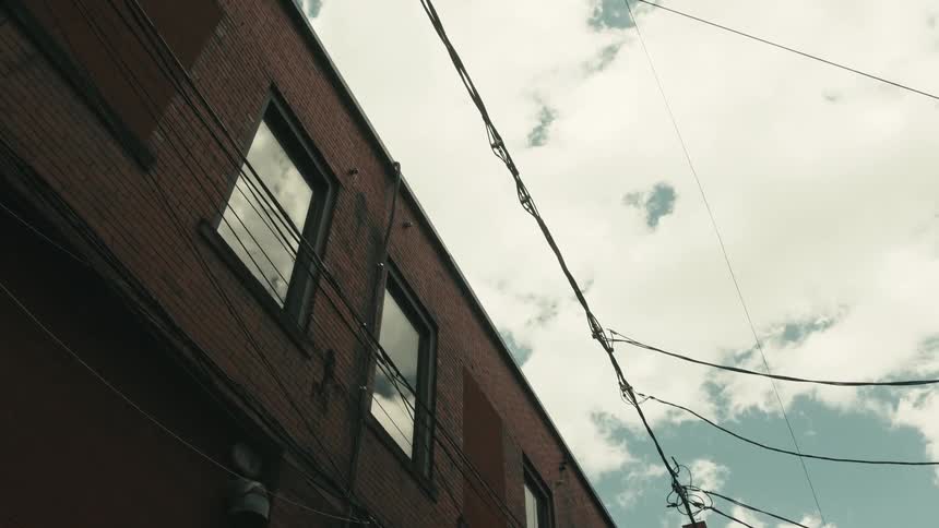 Power lines parallel a building with windows that reflect the sky
