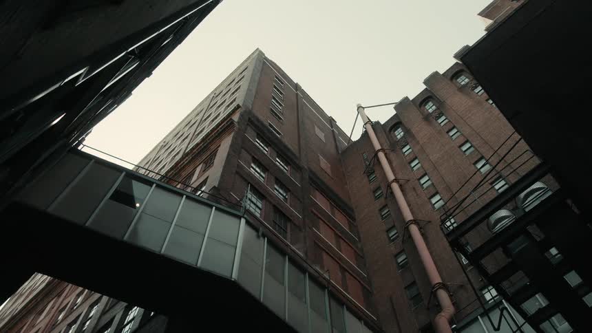 A glass walkway connects two buildings in the city