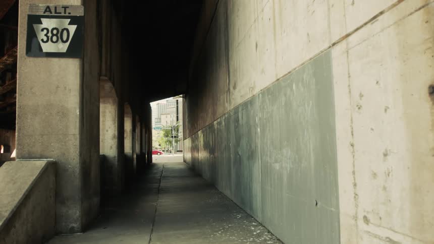 Red car crosses through the intersection at the end of the corridor passing through a structure