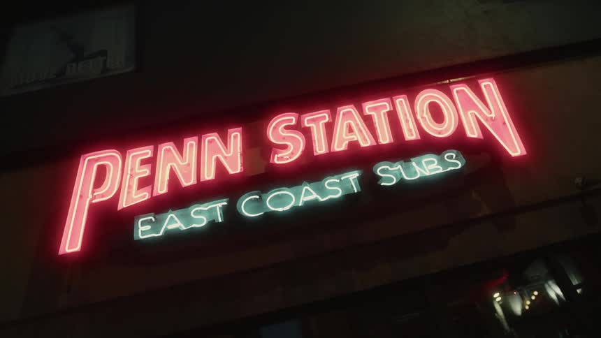 Penn station east coast subs storefront sign glows red and green at night