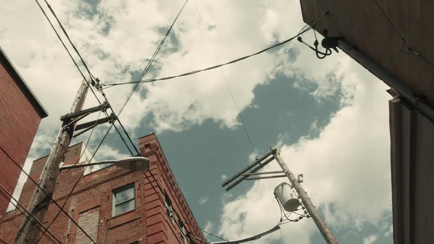 A window air conditioner outside a red brick building connected to other buildings through power liens