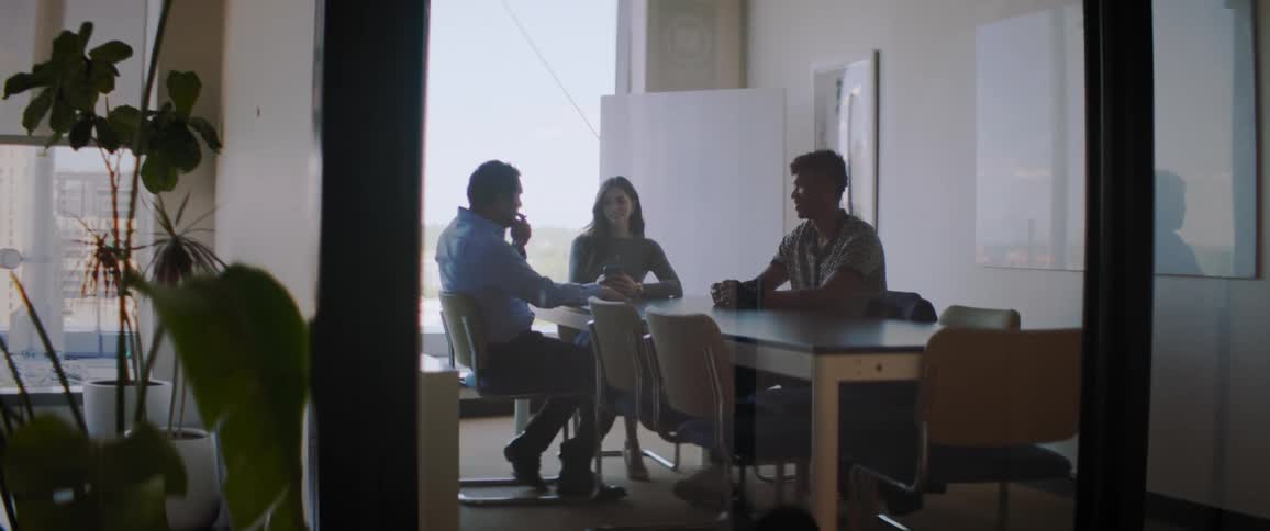 Group of three people sitting at an office table talking